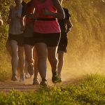A group of people running along a dusty trail in warm golden light