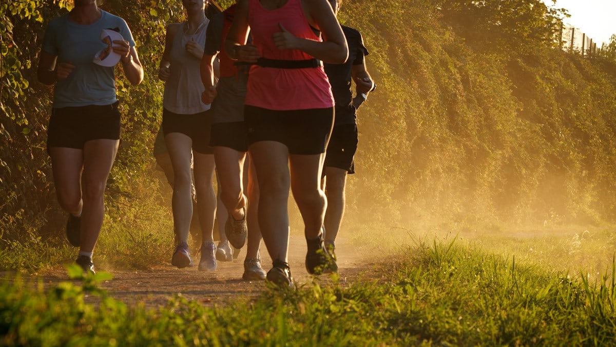 A group of people running along a dusty trail in warm golden light
