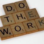 Creative arrangement of Scrabble tiles spelling 'Do the Work' on a white background.